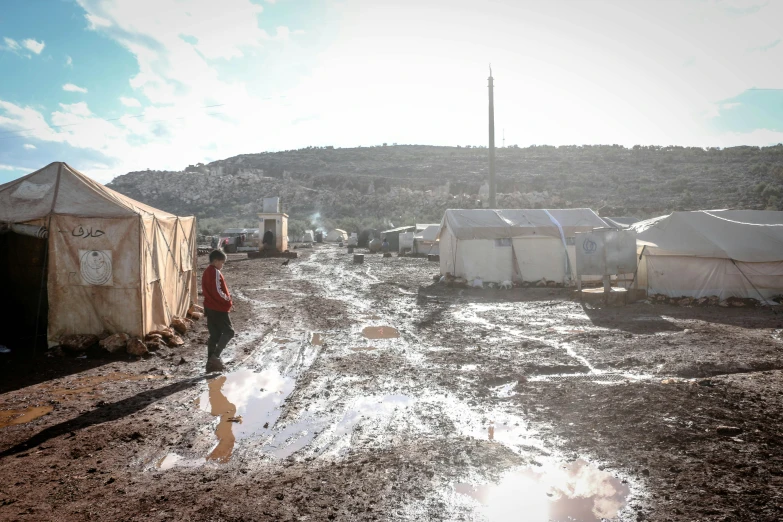 a man standing in a dirt road next to tents