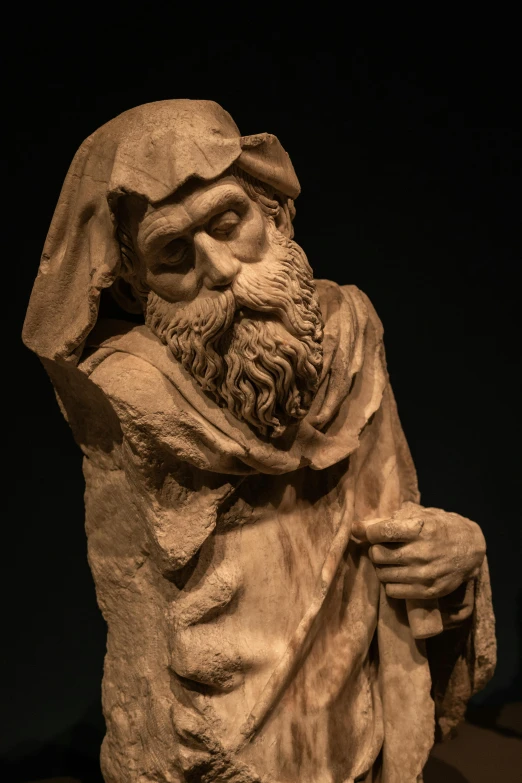a statue of a bearded god sitting in front of a dark background