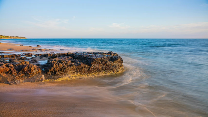 some rocks on the shore line and a blue sky