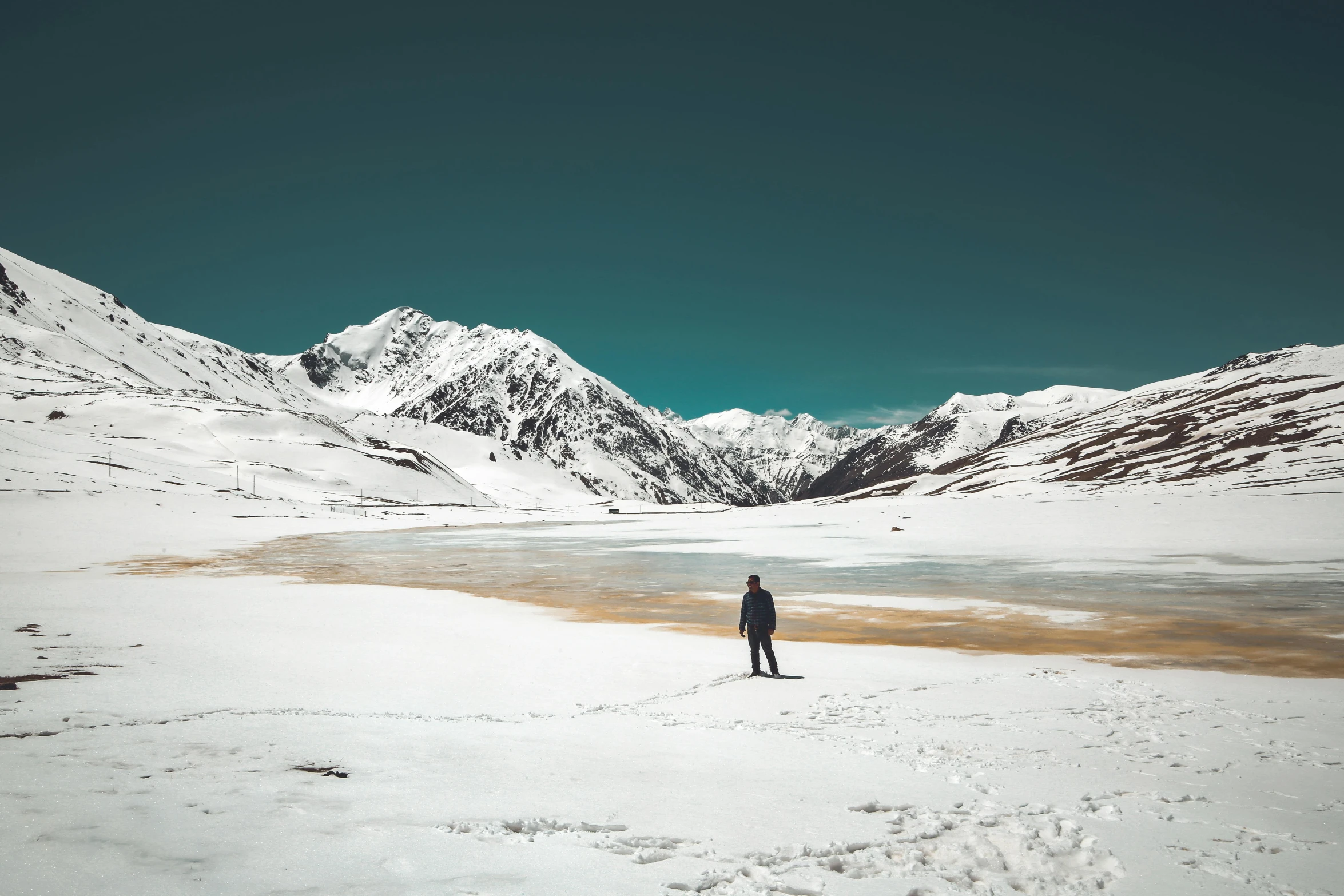 a person standing in the snow near mountains