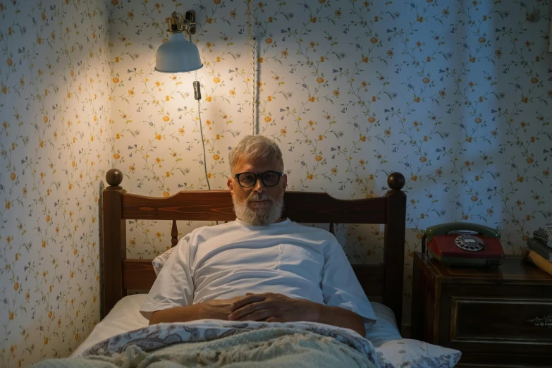 a man laying in bed with an alarm clock and light