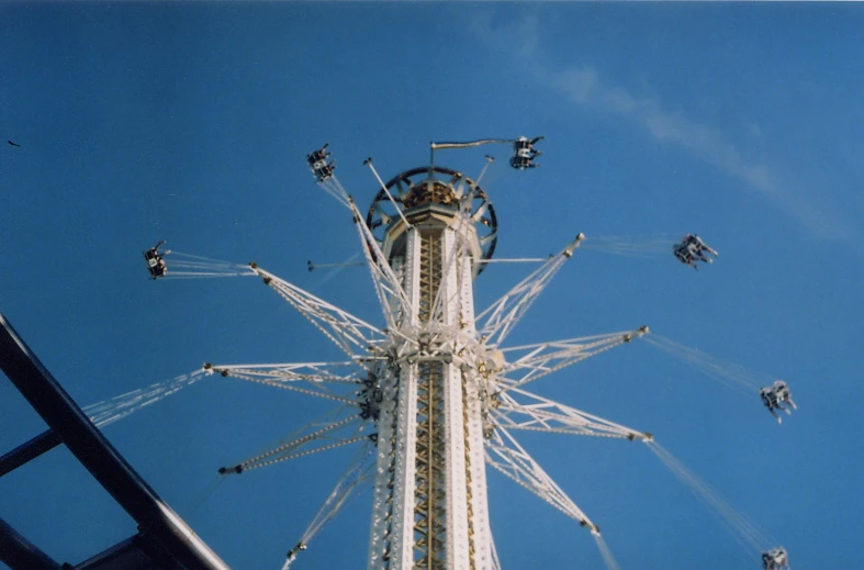 a very tall ferris wheel with lots of people standing around