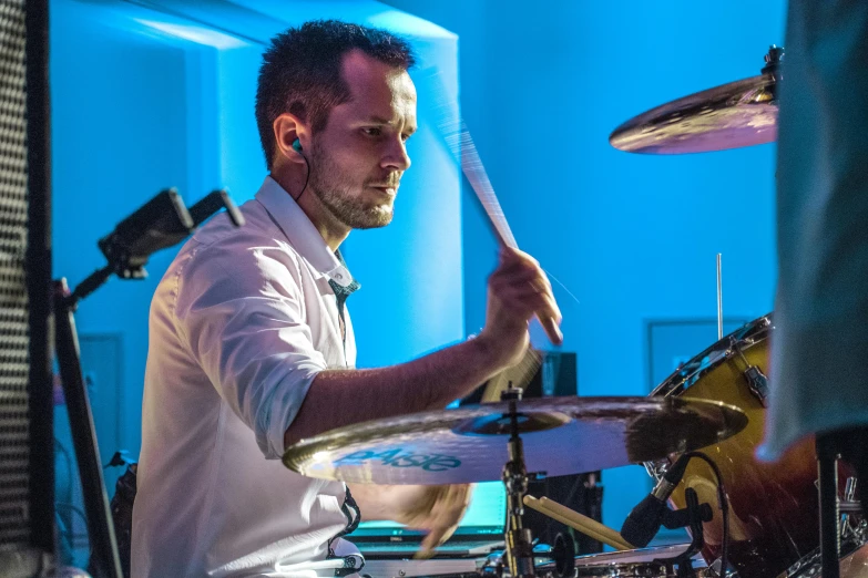 a man plays a drum set with his white kit