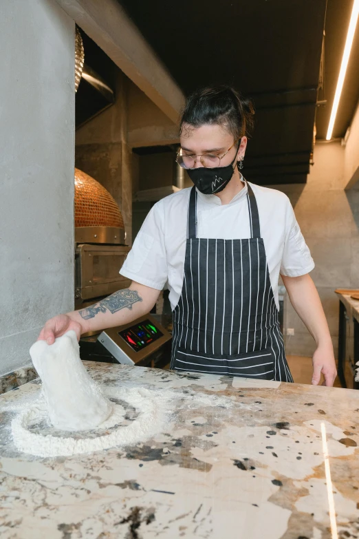 a person wearing a mask making food on a counter