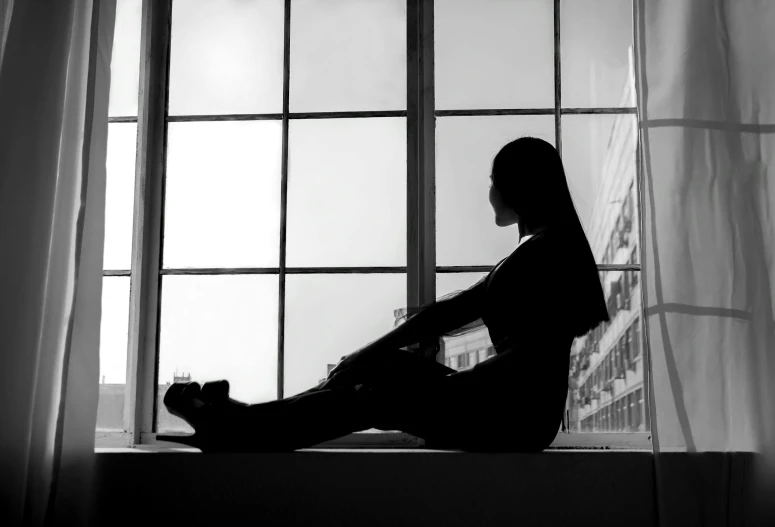 a woman sitting in the window sill looking out