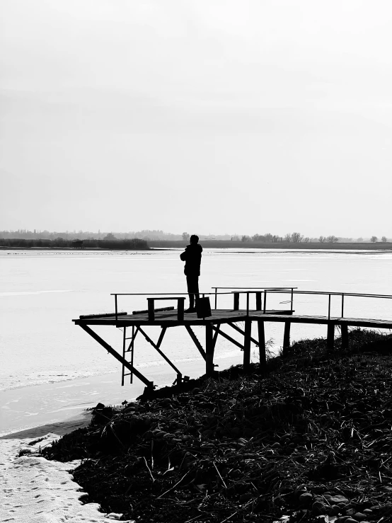 the two men are standing on the bridge by the water