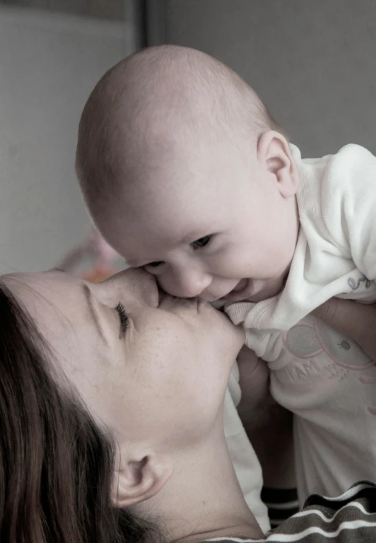 the baby's head is being kissed by its mother