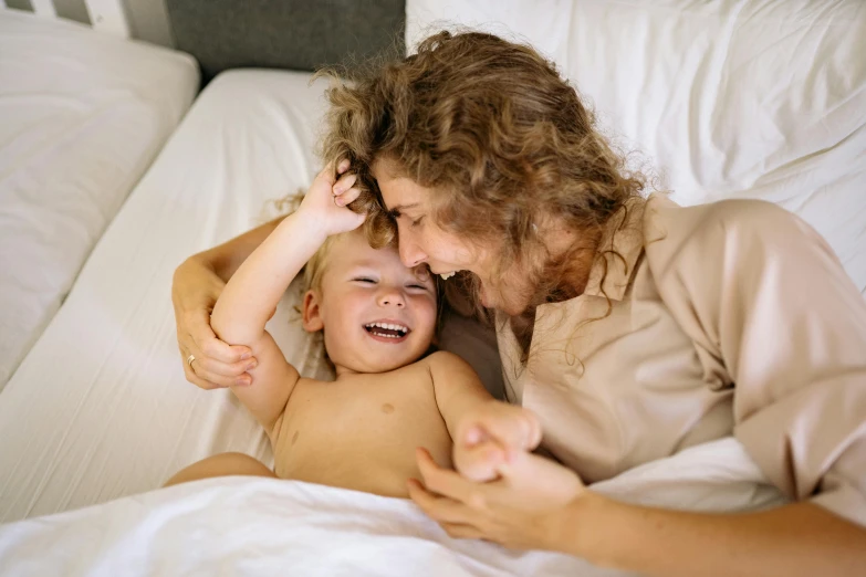 a smiling woman is laying down and hugging a 