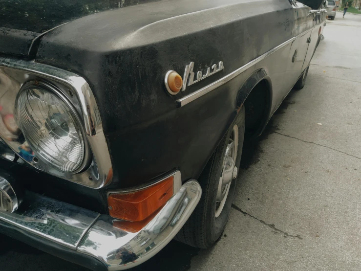 an old black car is parked on the side of the road