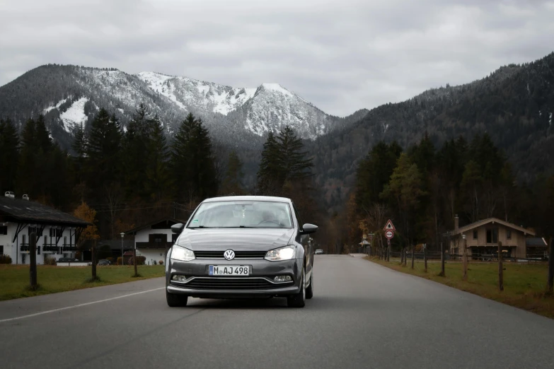 a car is driving down the road near the mountain range