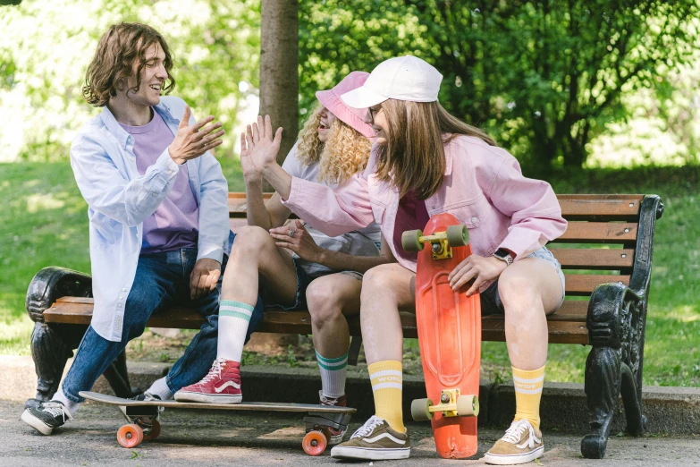 three people sitting on a bench talking with skateboards