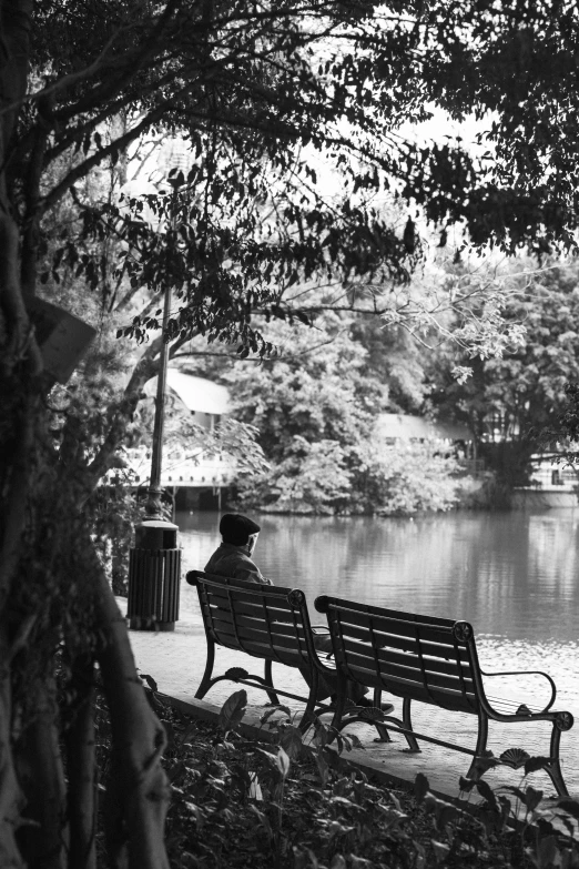 a person sitting on top of a wooden bench next to a body of water