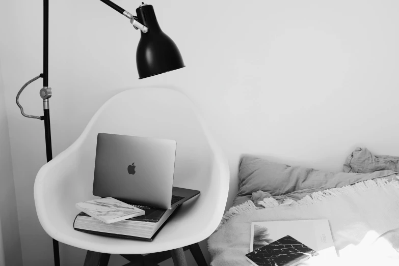 a desk with a laptop, book and lamp