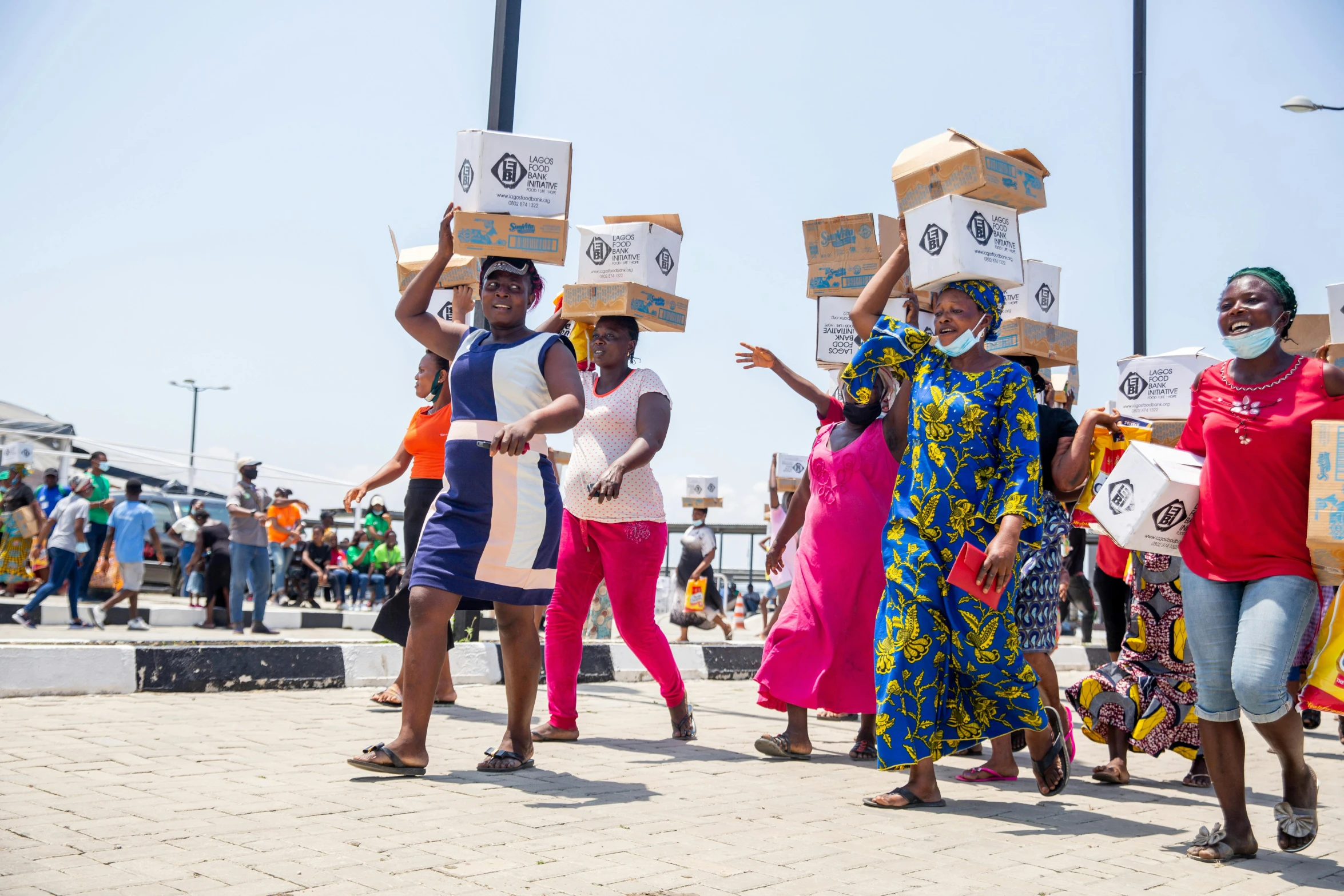 several women carrying boxes across a street