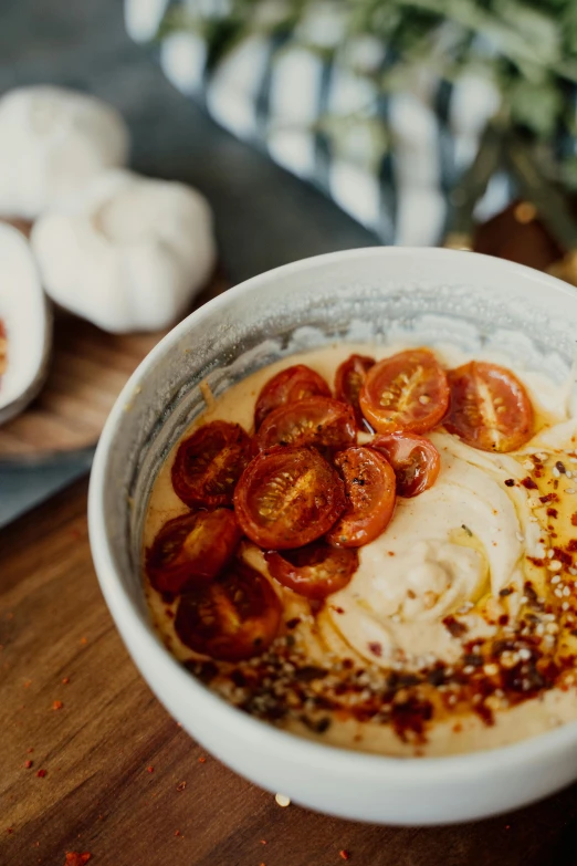 bowl with sauce, tomatoes and sliced garlic on top