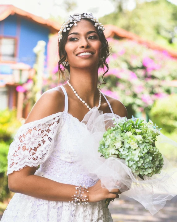 a bride smiles in front of a blue house