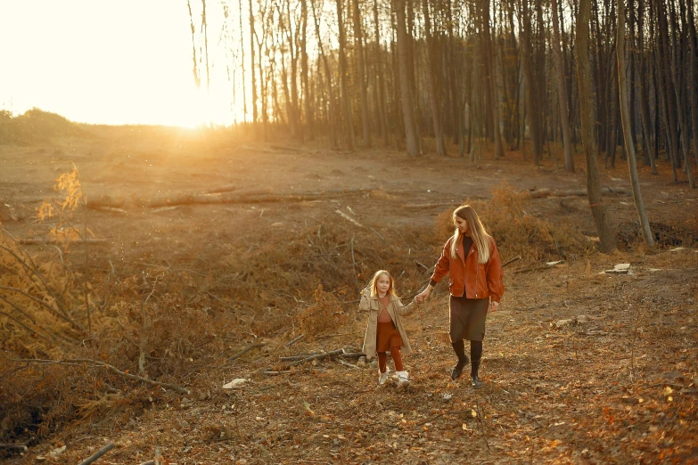 the woman and child are holding hands walking along a path