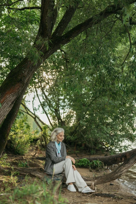 an older woman sitting on a park bench in the shade