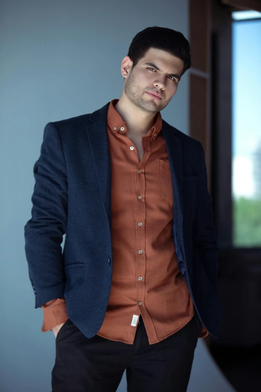 a man is standing in a room with a suit and a blazer