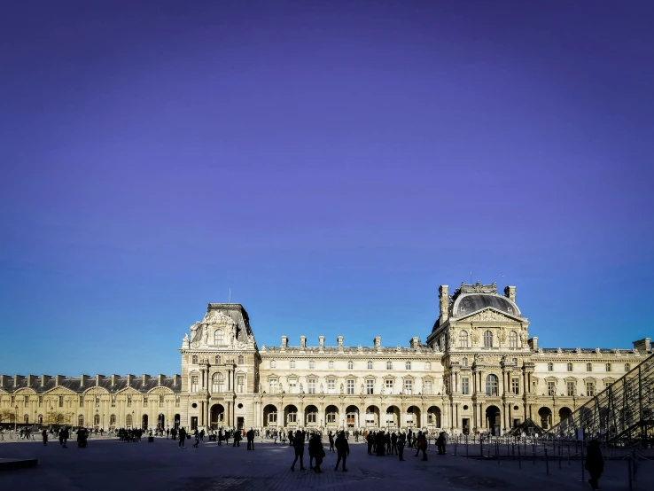 people are standing outside the building under a clear blue sky