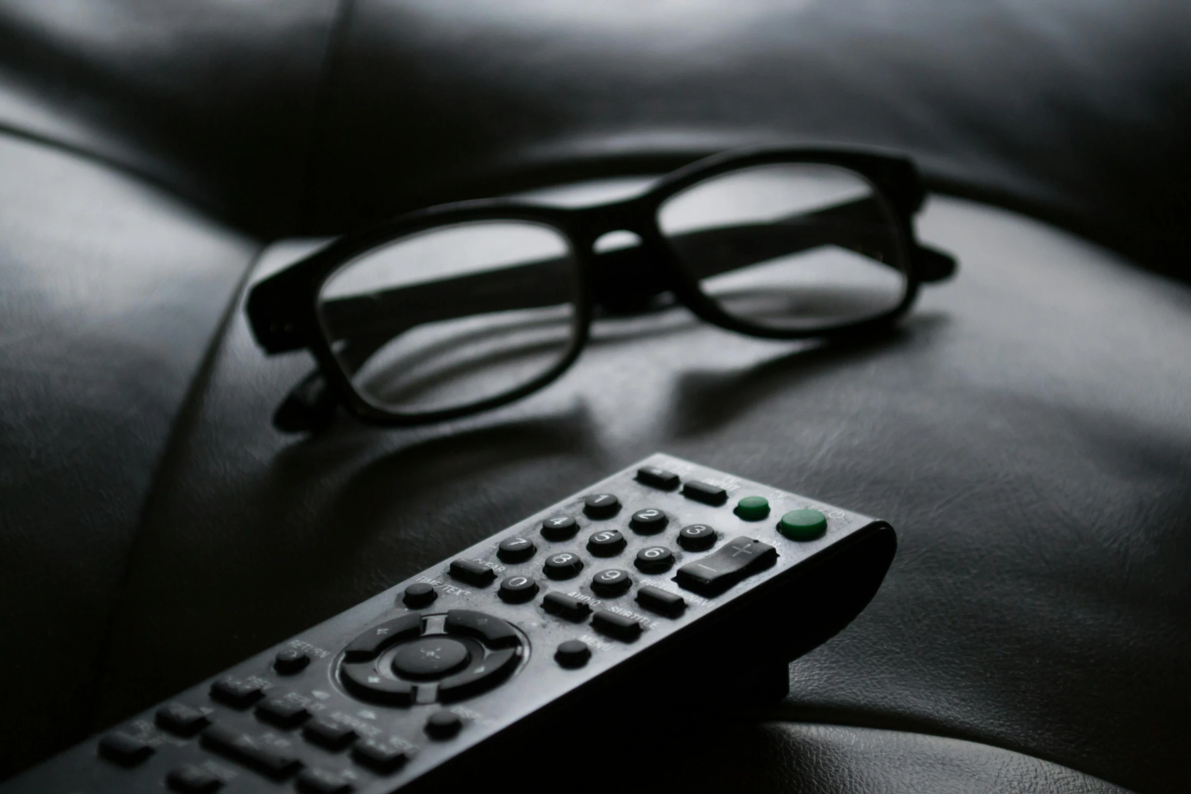 a remote control next to a pair of glasses