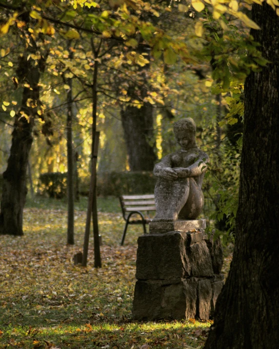 a statue sits on a stump in the park