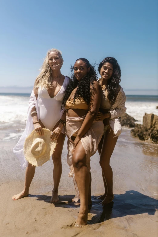 four women pose in front of the ocean