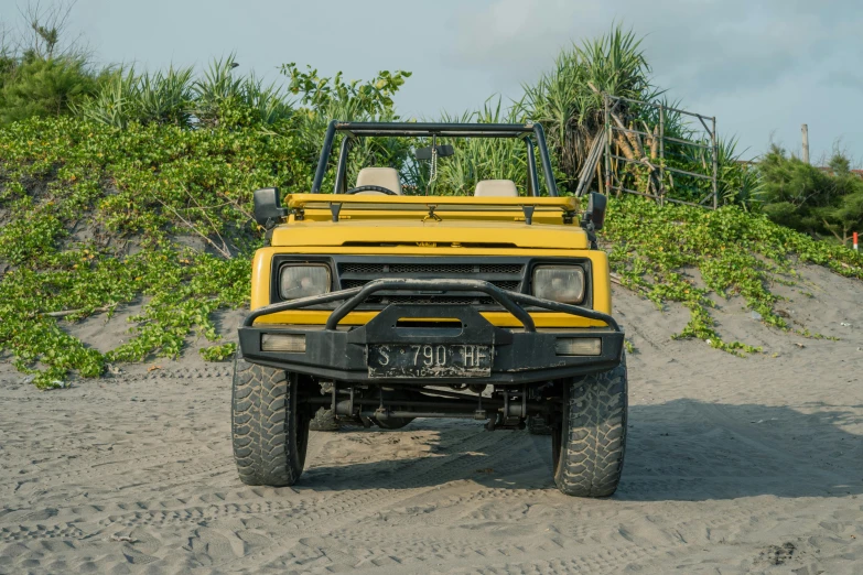 the front end of a yellow truck parked on the beach