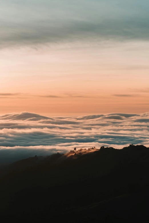 the top of the mountain is covered in low clouds