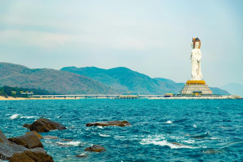 a statue stands on the shore near a beach