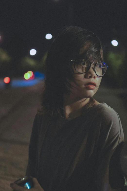 a woman wearing glasses standing outside at night