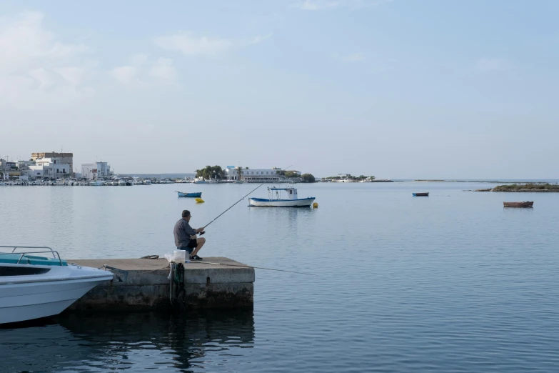 a man fishing from the dock in a body of water