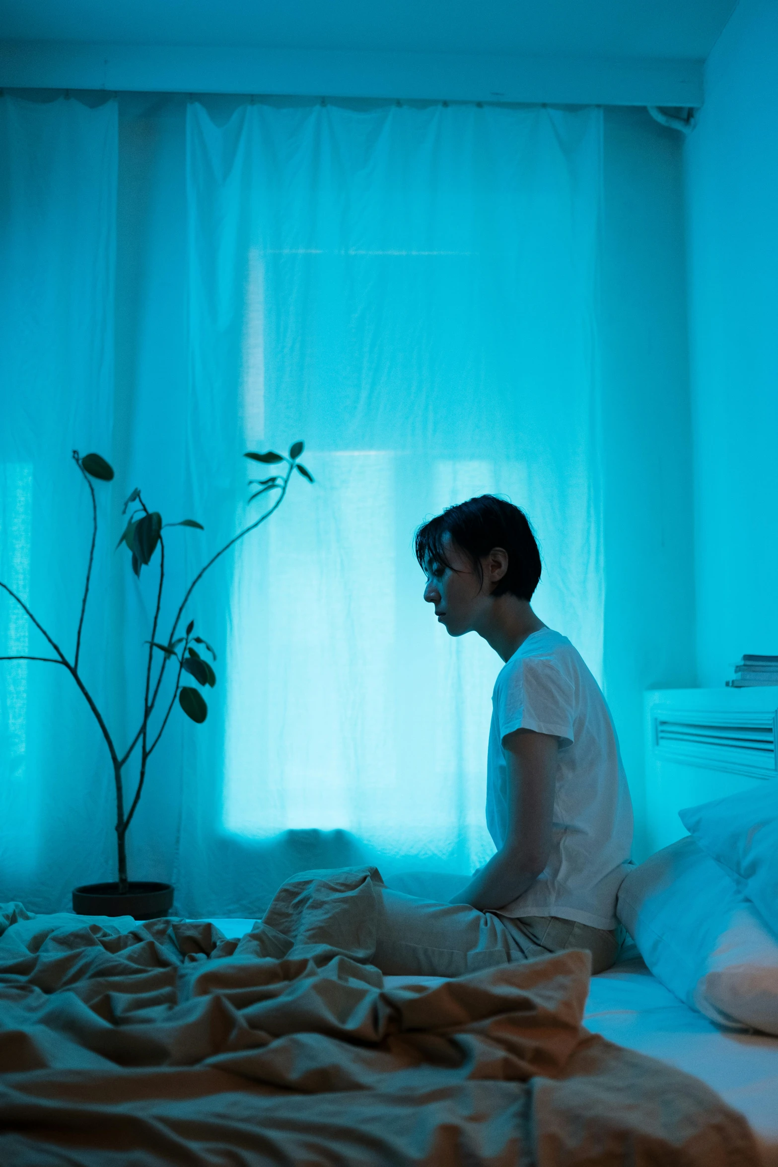 a man sitting on a bed in the darkness next to a window