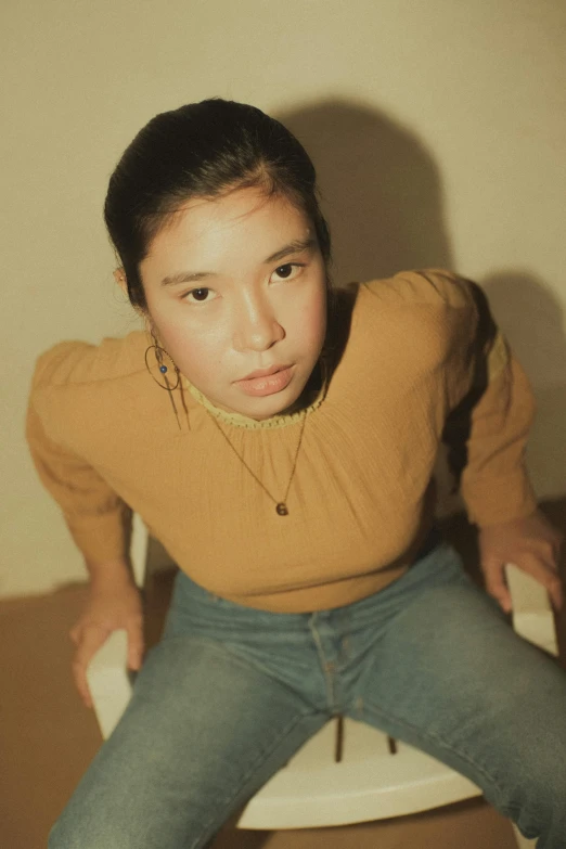 young woman on a stool staring at camera