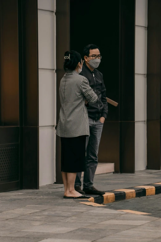 a man and woman standing on sidewalk wearing masks