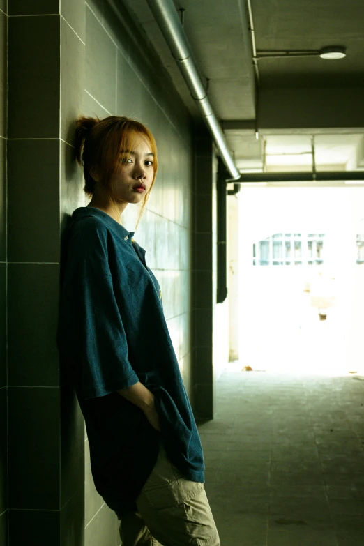 a woman is leaning against a wall in an empty hallway