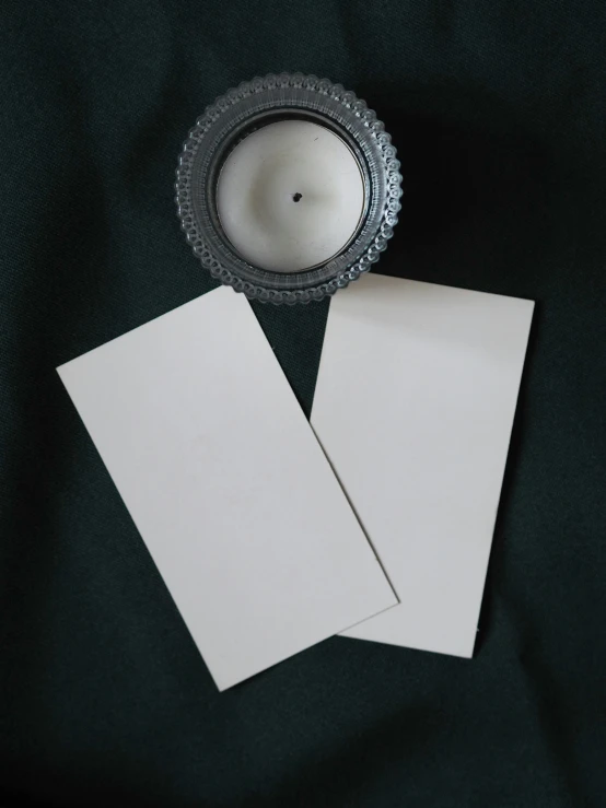 two paper pieces next to a candle on top of a green sheet of paper