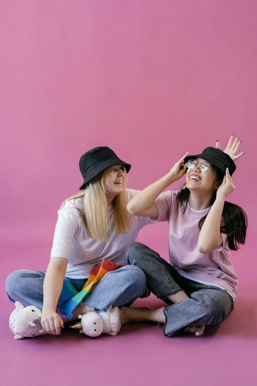 two girls are sitting together with hats on