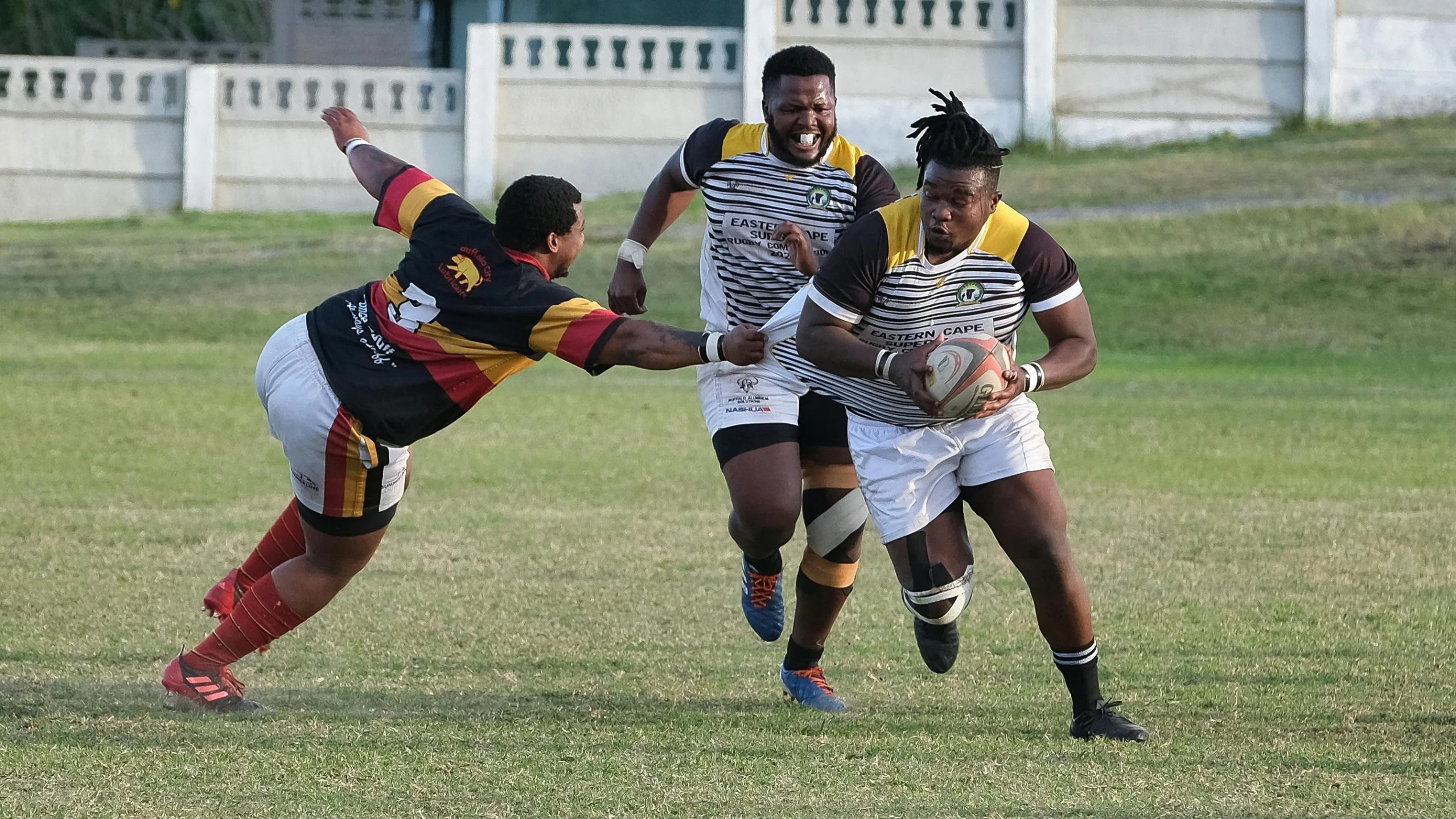 an action s of three men playing football in the field