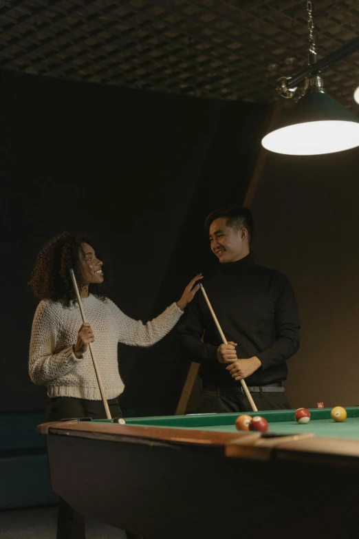 two people who are standing by a pool table