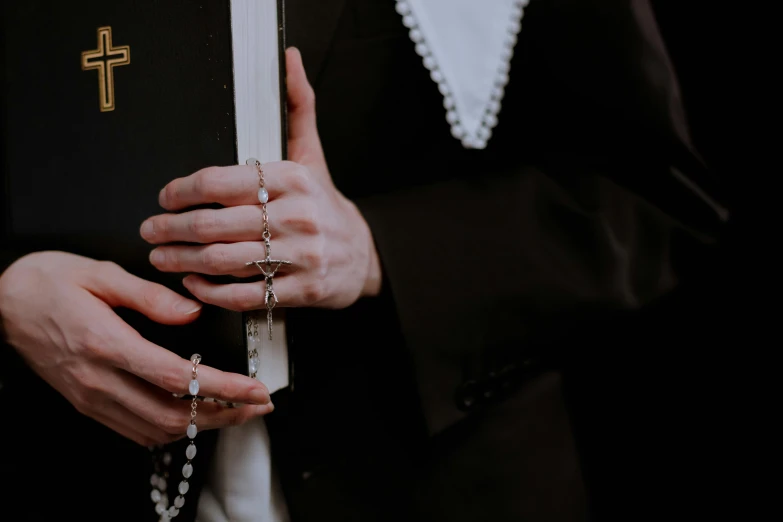 the woman is holding the rosary while wearing a black jacket