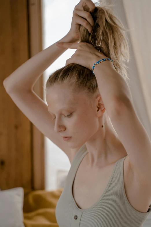 a woman is putting her hair in a messy ponytail