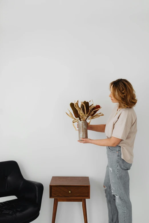 a woman stands next to a small table holding a plant