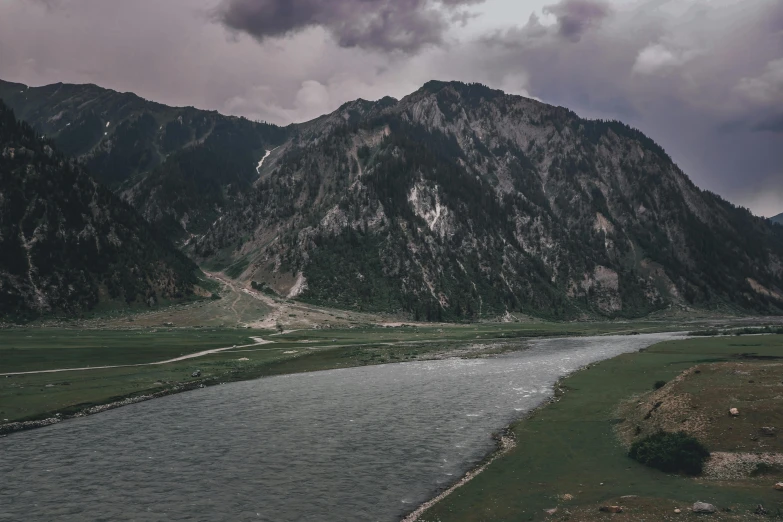 there are mountains surrounding a river on this cloudy day