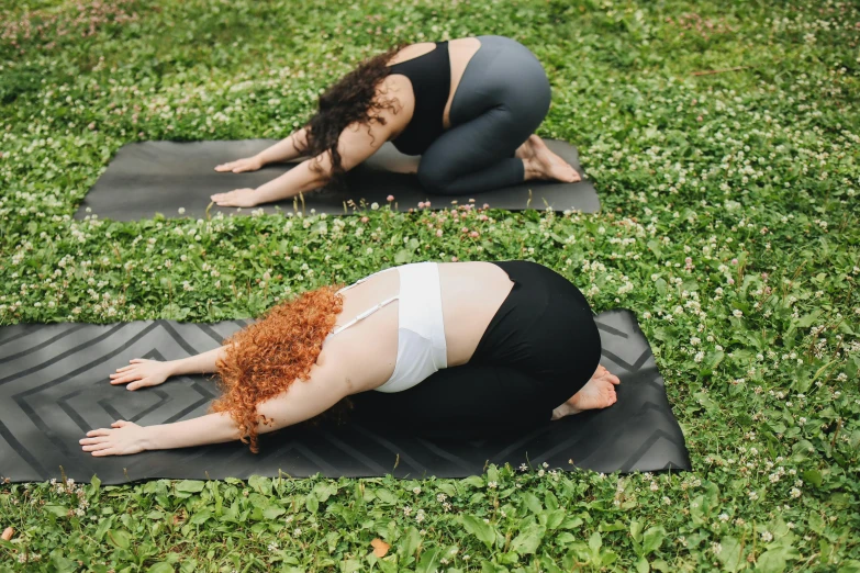 two women in sports s are performing yoga in the grass