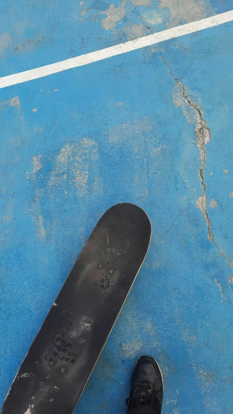 someone standing next to a longboard on the street