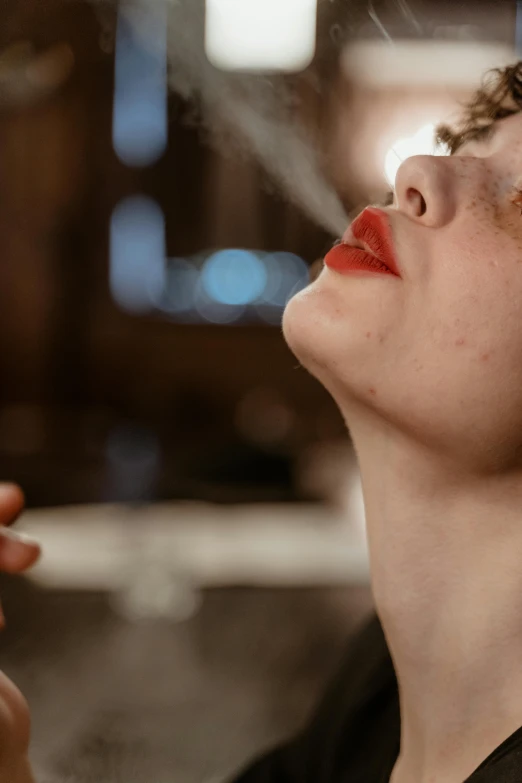 a woman smoking a cigarette in front of a window