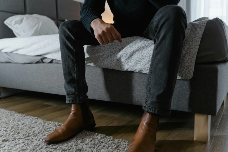 a person sitting on a grey couch with foot rest