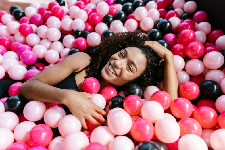 a woman is laying in an assortment of multicolored balls