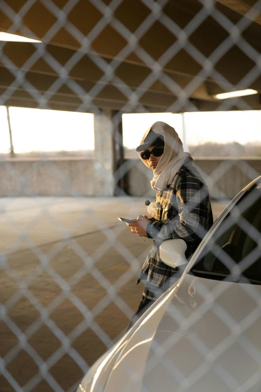 a woman checking her cellphone while leaning on a white car